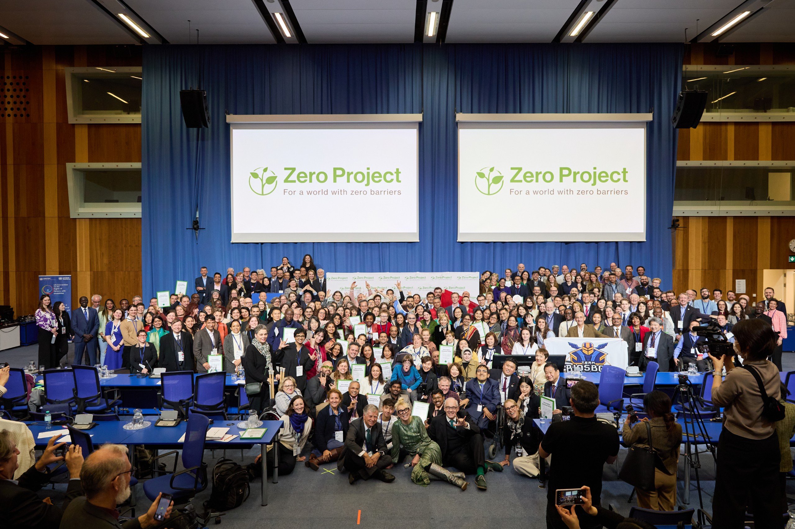 A group of people at an award ceremony standing in front of a large screen displaying the words 'Zero Project'.